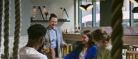 Un groupe de personnes est réuni dans un restaurant à l’ambiance moderne, caractérisé par des murs en briques apparentes et un éclairage suspendu.