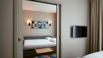 A hotel room with a bed, a TV mounted on the wall, and abstract art on the wall.