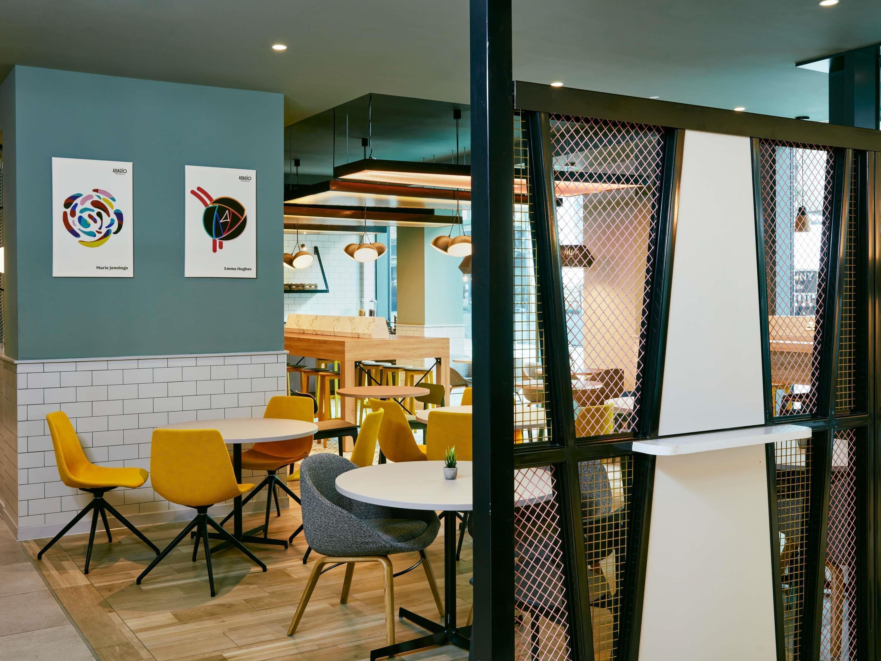A modern dining area with yellow chairs, a round table, and artwork on the wall.