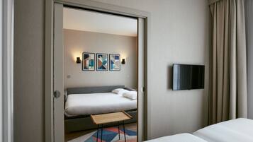 Una habitación de hotel con cama, televisión en la pared y una mesita.