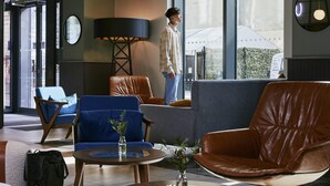 A modern lobby with leather seating, a round table with a vase, and large windows. - Aparthotel Adagio Glasgow Central (Glasgow)