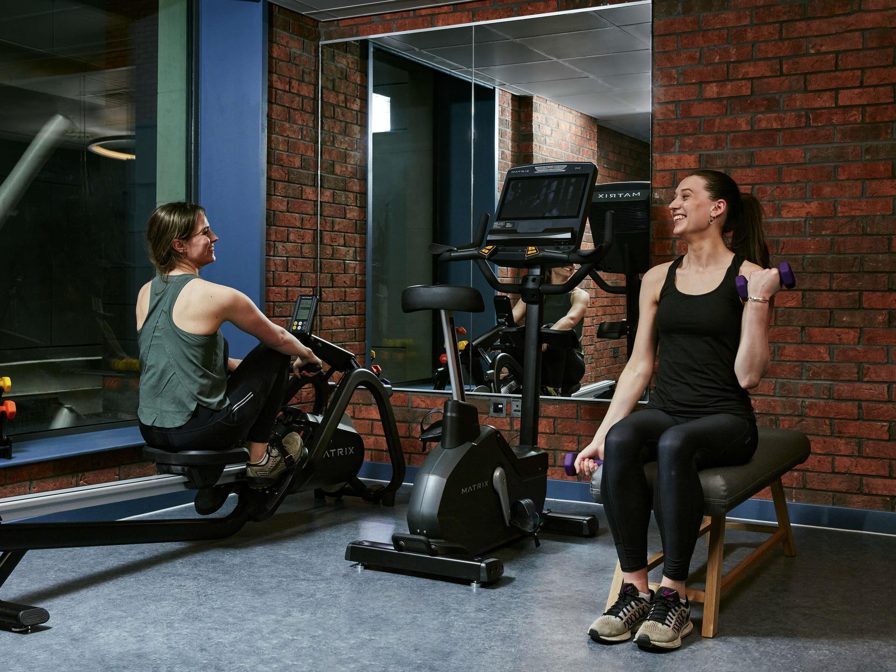 A gym with exercise equipment, a bench, and a brick wall.