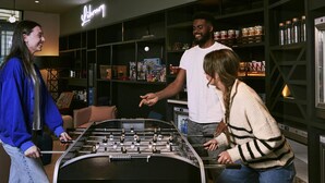 A room with a foosball table, shelves with various items, and a neon sign that reads "Shop". - Aparthotel Adagio Glasgow Central (Glasgow)