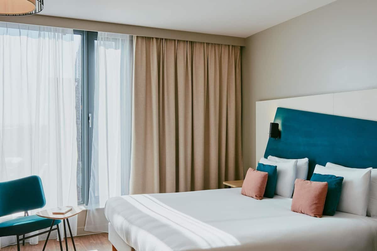 Una habitación de hotel con una cama grande, un escritorio y una silla.