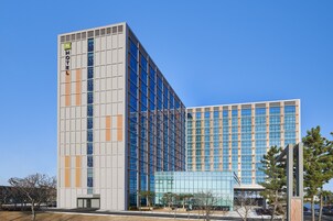 Un hôtel moderne avec une façade en verre et une grande enseigne « HÔTEL » bien visible sur le côté.