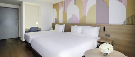 A hotel room with a large bed, a bedside table with a vase of flowers, and a wall with abstract art.