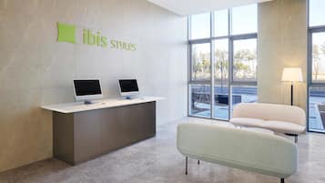 A reception desk with two monitors, a green sign above it, and a modern chair.