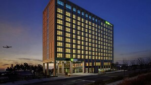 Un hôtel moderne doté d’un grand nombre de fenêtres, d’une entrée imposante et d’une enseigne verte indiquant son nom.