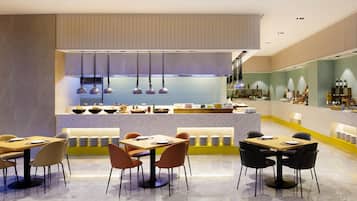 A modern restaurant with a central counter, multiple seating areas, and a bar.