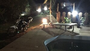 Ein Außenbereich bei Nacht mit Pool, einer Bank und einem Motorrad.