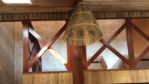 Eine Holztreppe führt zu einem Schlafbereich mit einem Reetdach.