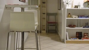 Un pasillo con una silla blanca, una estantería con libros y un armario blanco.