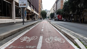 Una calle urbana con un carril bici, edificios y un automóvil estacionado.