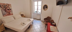 Une chambre d’hôtel avec un lit, une chaise, un bureau, une fenêtre et un tableau au mur.