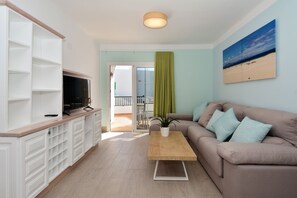 Un salon moderne avec un canapé, une table basse et un téléviseur posé sur un meuble.