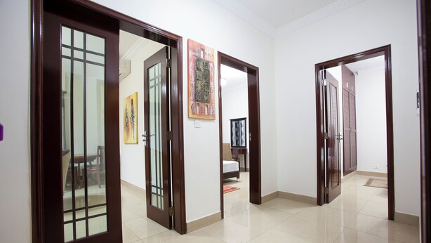 A hallway with wooden doors, a tiled floor, and a painting on the wall.