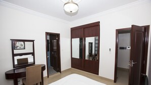 A hotel room with a bed, a desk with a chair, a large mirror, and two doors.