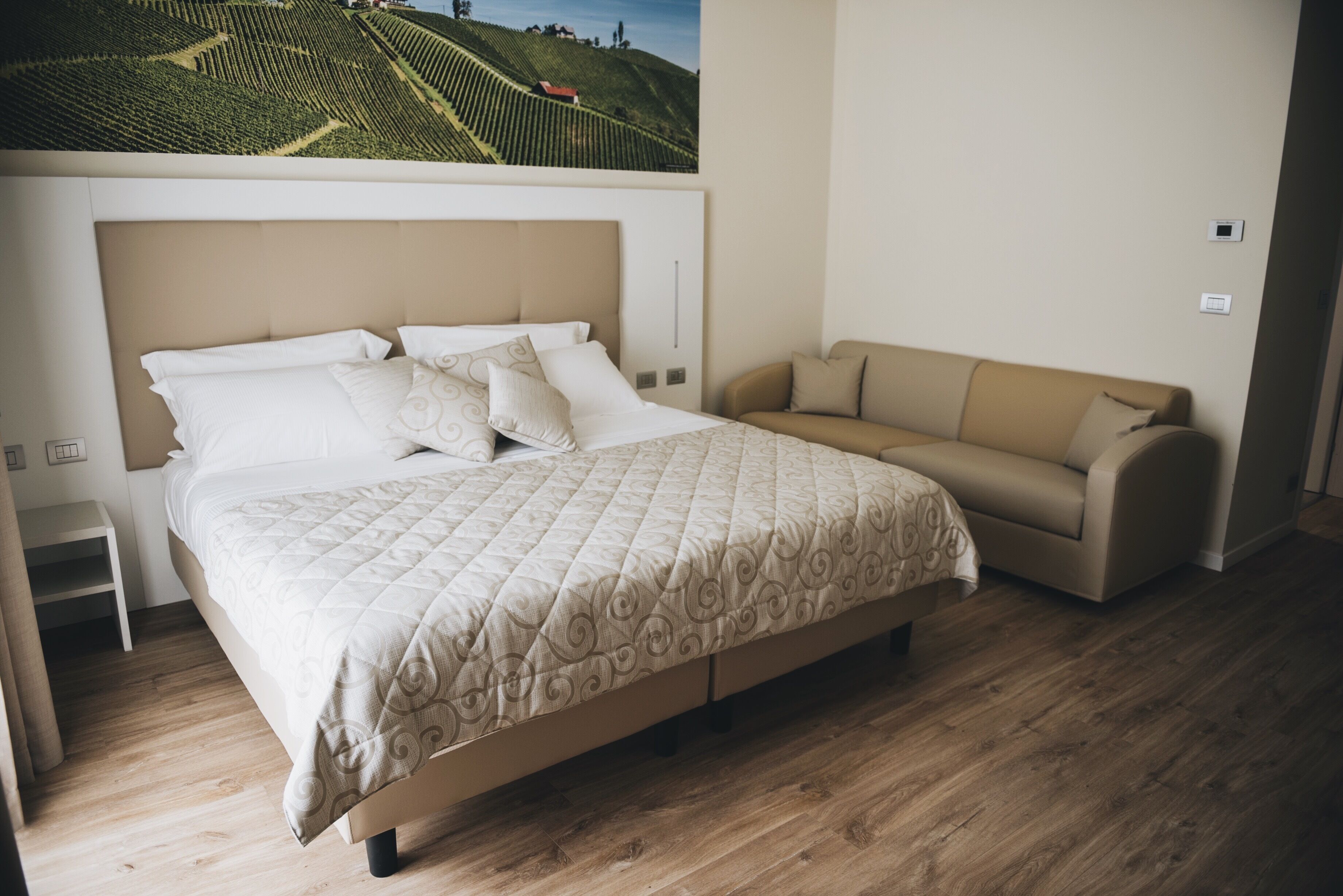 A bedroom with a bed, a sofa, and a wall-mounted TV.