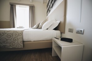 A neatly arranged hotel room with a bed, bedside table, and a window with curtains.