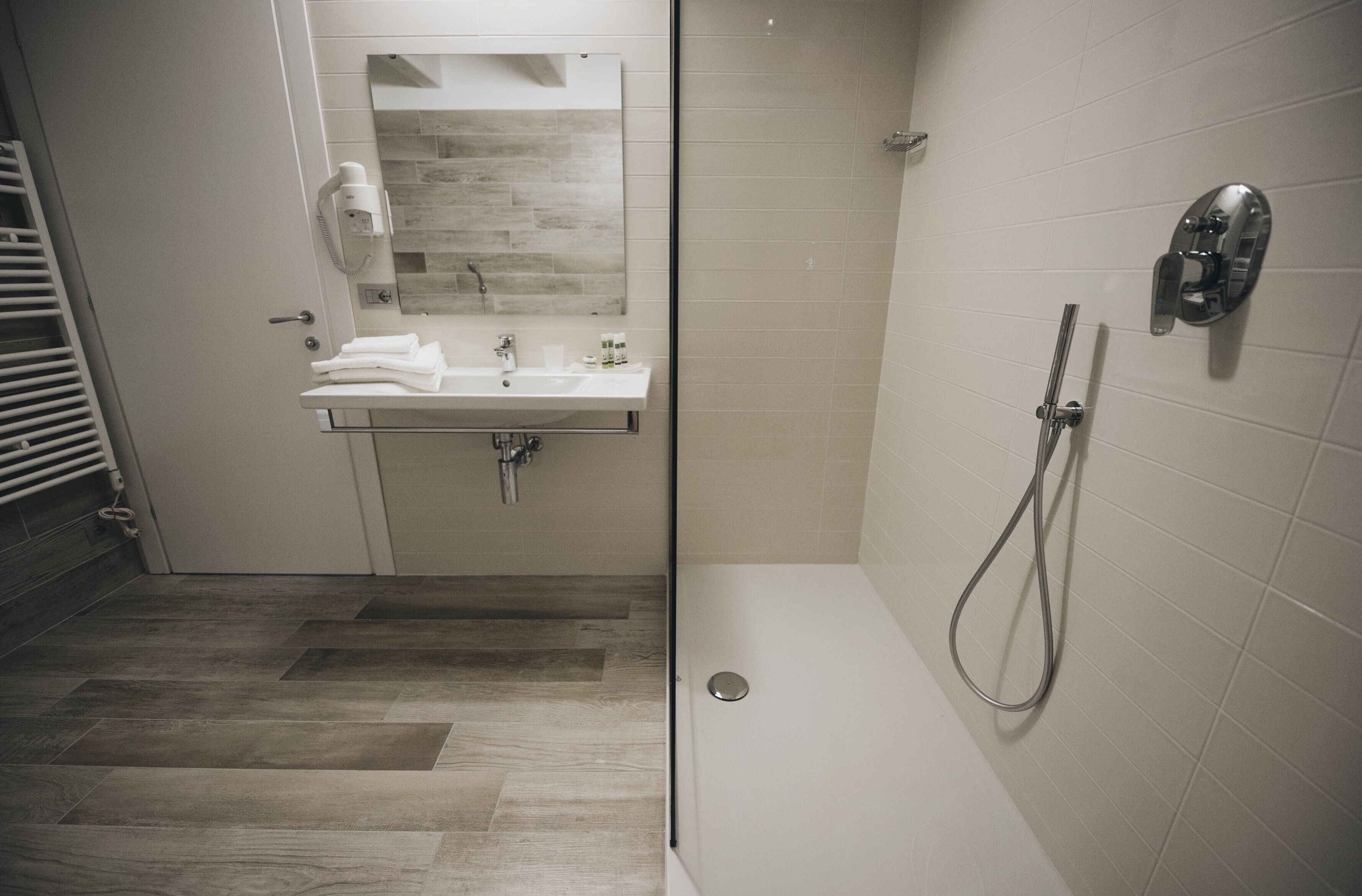 A modern bathroom with a shower, a sink with a mirror, and a towel rack.