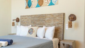 A neatly made bed with a patterned headboard, a decorative pillow, and a blue blanket. - Villa Dioni-Ocean view from every room, spacious and very clean. (Magganos)