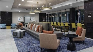 A modern lobby with a seating area, a reception desk, and a large window. - Home2 Suites by Hilton Covington (Covington)