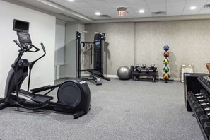 A gym with a treadmill, weight bench, and various exercise equipment. - Home2 Suites by Hilton Covington (Covington)