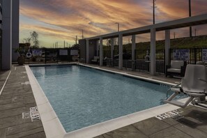 A swimming pool with a sunset view, lifeguard signs, and lounge chairs. - Home2 Suites by Hilton Covington (Covington)