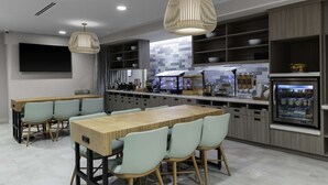 A modern kitchen with a central island, built-in shelves, and a refrigerator. - Home2 Suites by Hilton Covington (Covington)