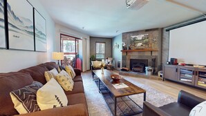 A living room with a fireplace, a sofa, a coffee table, and a TV. - Unique Cabin in Quiet Forest Setting. Near Walking/Biking Trails. Summer Pool (Mammoth Lakes)