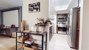 A modern kitchen with stainless steel appliances, a wooden dining table, and a decorative sign on the wall. - Unique Cabin in Quiet Forest Setting. Near Walking/Biking Trails. Summer Pool (Mammoth Lakes)