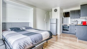 Une chambre compacte comprenant un lit et une petite kitchenette.