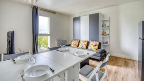 Une cuisine moderne avec une table à manger pour deux personnes, un four encastré et une grande fenêtre.