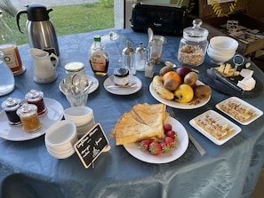 A breakfast table with various food items, including fruits, bread, and condiments. - Fleur & Mer (Montfarville)
