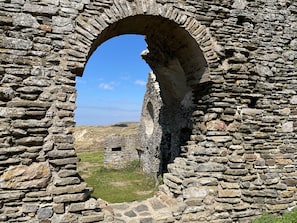 A stone archway leading to a grassy landscape. - Fleur & Mer (Montfarville)