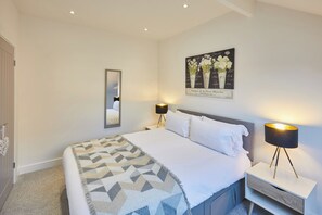Une chambre à coucher avec un lit, des lampes de chevet, un miroir fixé au mur et un tableau encadré.