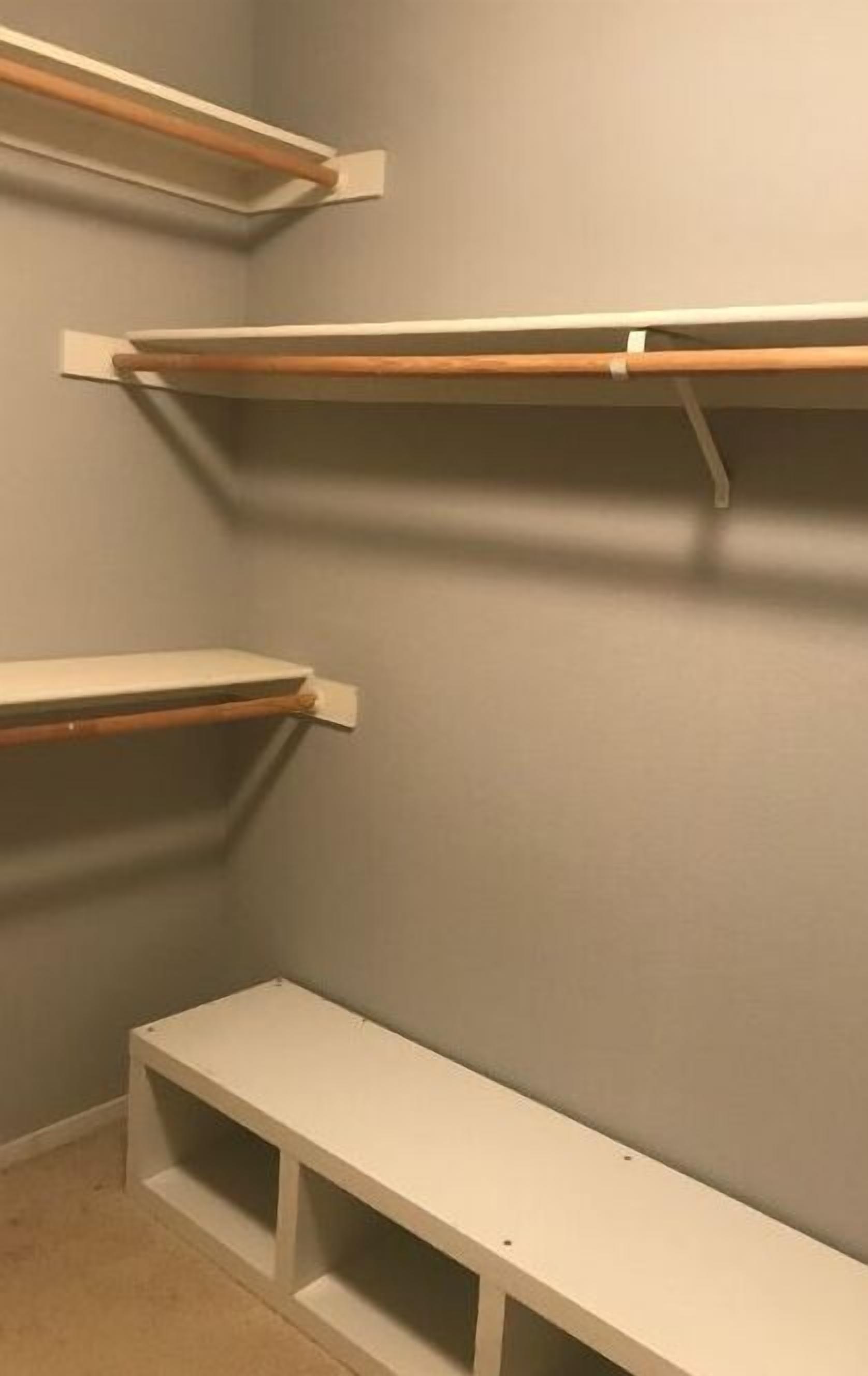 Un coin de pièce avec trois étagères blanches adossées à un mur gris.