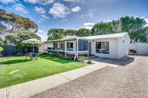 Une maison moderne à deux étages, dotée d’un patio couvert, d’une pelouse bien entretenue et d’une allée en gravier.