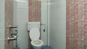 Un baño pequeño y cerrado con inodoro, dispensador de desinfectante para manos y portaescobillas.