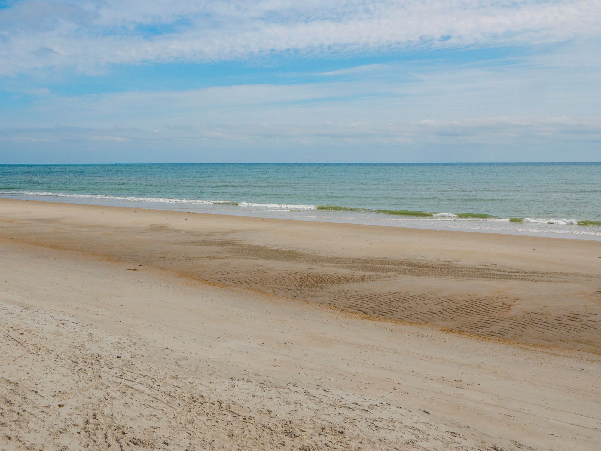 Une plage dotée d’un large rivage sablonneux et de vagues douces.
