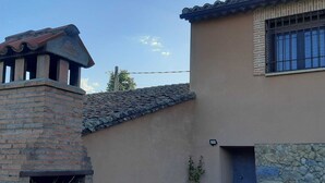 A building with a stone facade, a tiled roof, and a blue door. - The flax orchard. (Candeleda)
