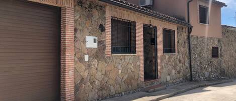 Um edifício de dois andares com fachada de pedra, porta de garagem e chaminé.