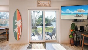 Una habitación con una tabla de surf, un televisor mostrando una escena de playa y un letrero que dice "Beach".