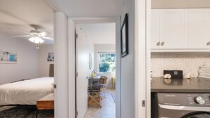 Un dormitorio con cama, escritorio y lavadora.