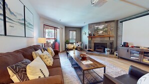 A spacious living room with a fireplace, a sofa set, a coffee table, and a television.