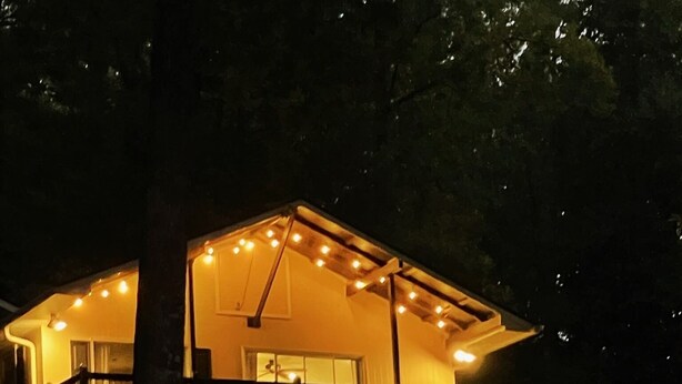 Een woonhuis met twee verdiepingen en een balkon, verlicht met lichtslingers.