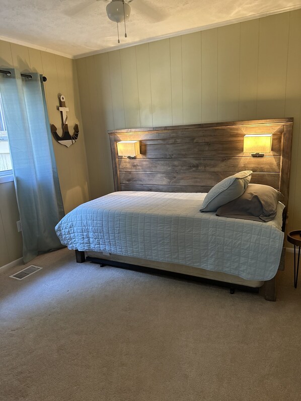 A bedroom with a wooden headboard, a quilted bedspread, and two bedside lamps.