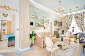 Un salon spacieux agrémenté d’un grand miroir, d’un canapé, d’une table basse et d’un coin repas avec des tabourets de bar.