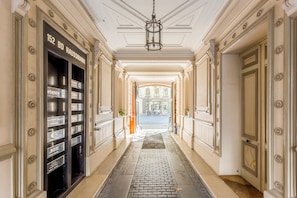 Classic corridor with doors leading to various rooms, featuring a patterned floor and decorative ceiling.