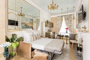 Une chambre d’hôtel luxueuse dotée d’un grand lit, d’un coin salon avec une table et des chaises, d’une cheminée et d’un téléviseur.